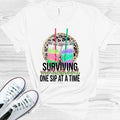 Surviving Motherhood One Sip at a Time Graphic Tee product image 1